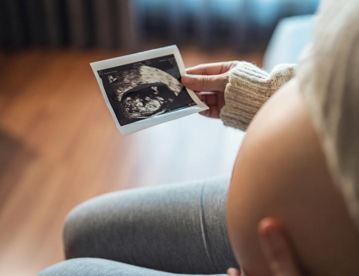Mujer embarazada que mira su informe de ultrasonido.