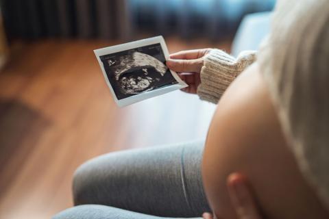 Mujer embarazada que mira su informe de ultrasonido.